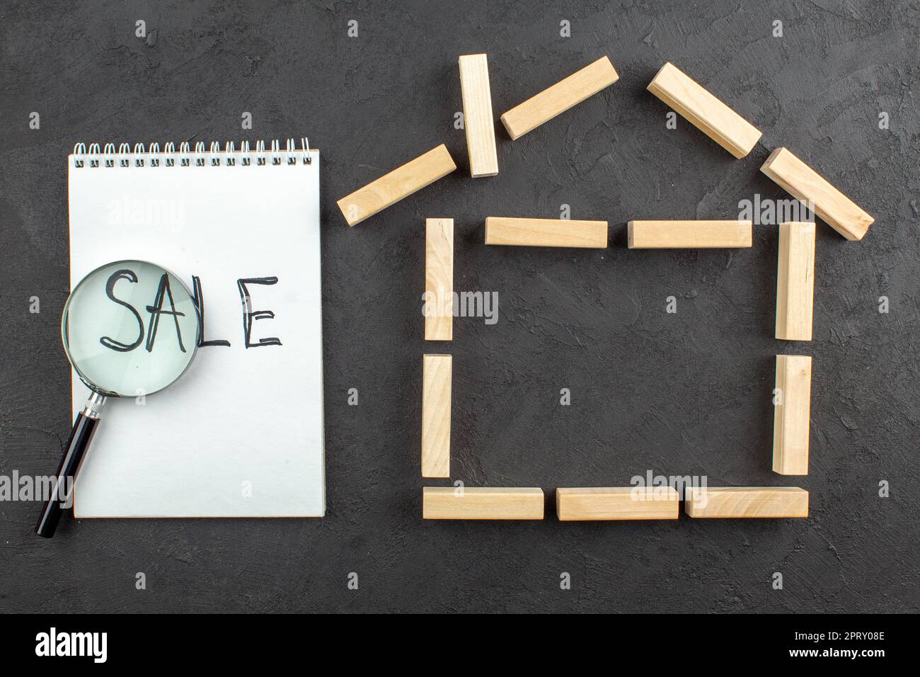 top view house shaped wood blocks sale written on notebook lupa on