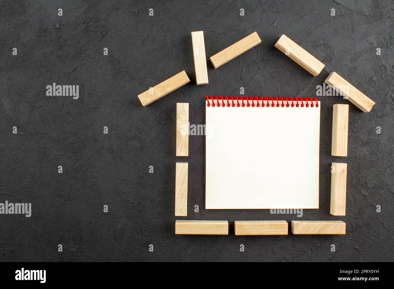 top view notebook in house shaped wood blocks on black background copy