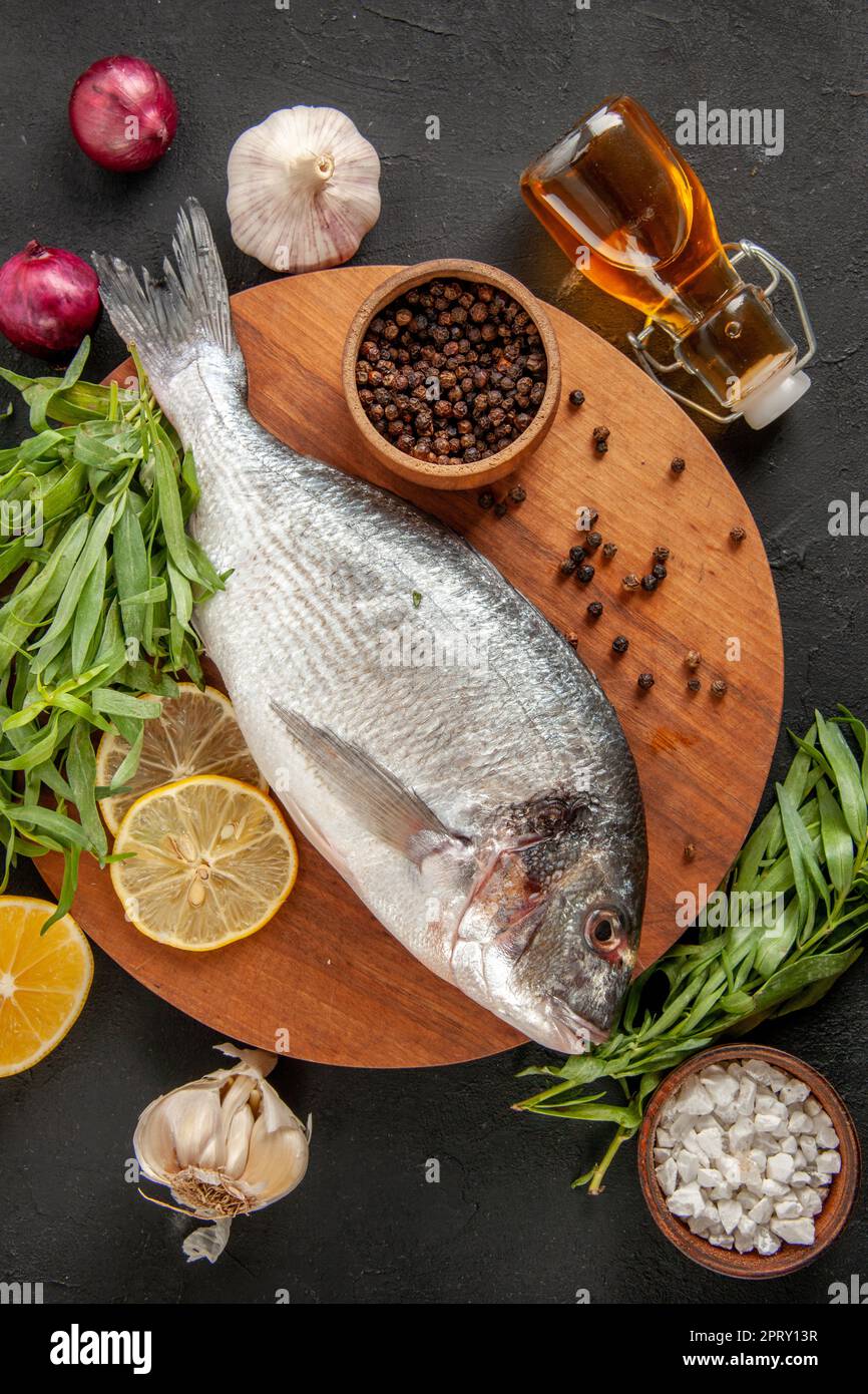 top view tarragon fresh raw fish black pepper bowl on round wood board ...