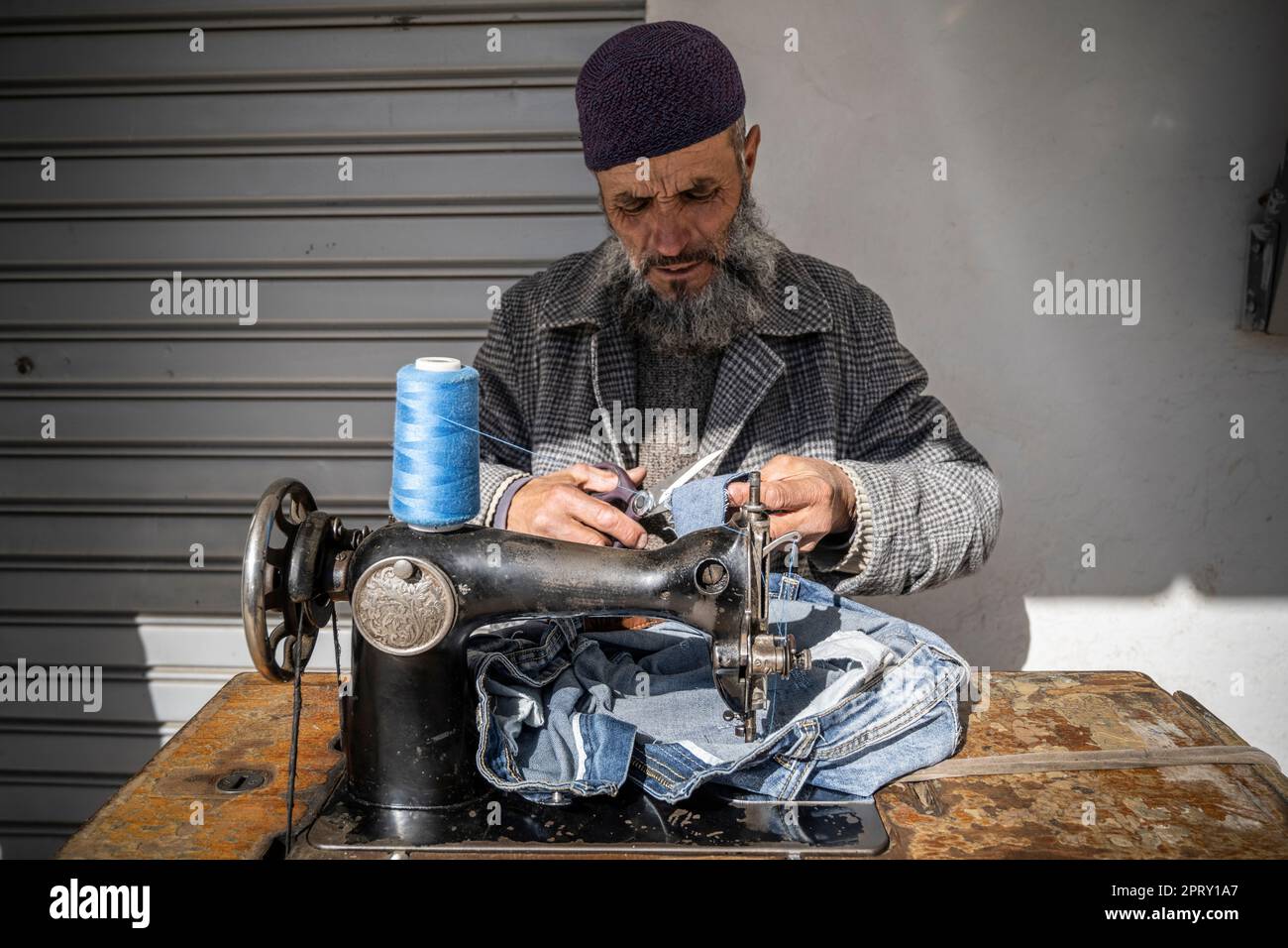 Tailor repairing clothes with his sewing machine in a street stall. Stock Photo