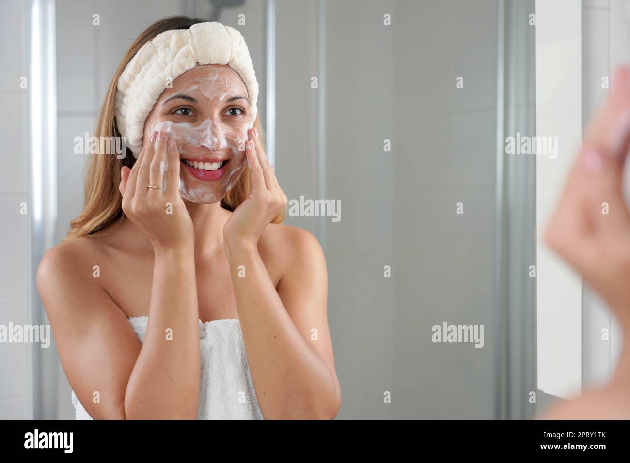 Smiling candid girl washing face foaming soap scrubbing skin. Young