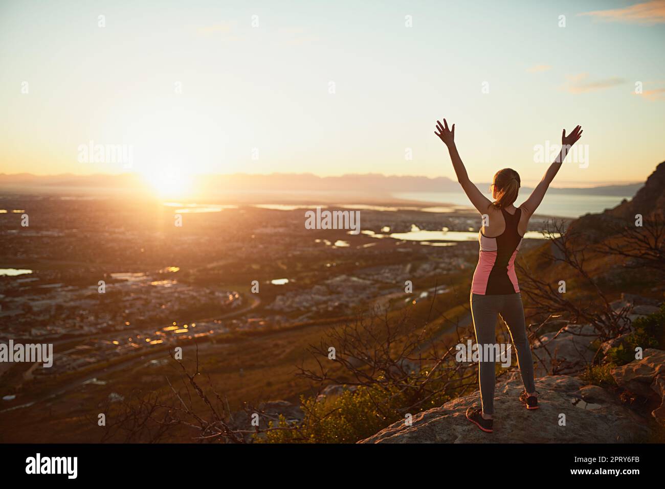 Ultimate freedom. Rearview shot of a sporty young woman standing outdoors with her arms outstretched Stock Photo