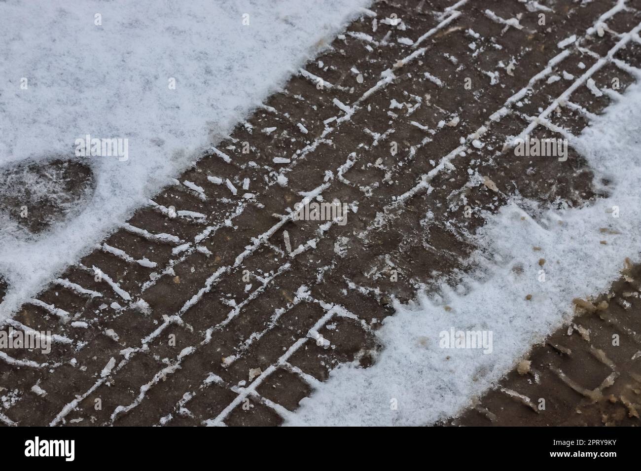 Car tracks on a snowy road. Slippery road, danger, risk of skidding. Traces of winter tire treads. Stock Photo
