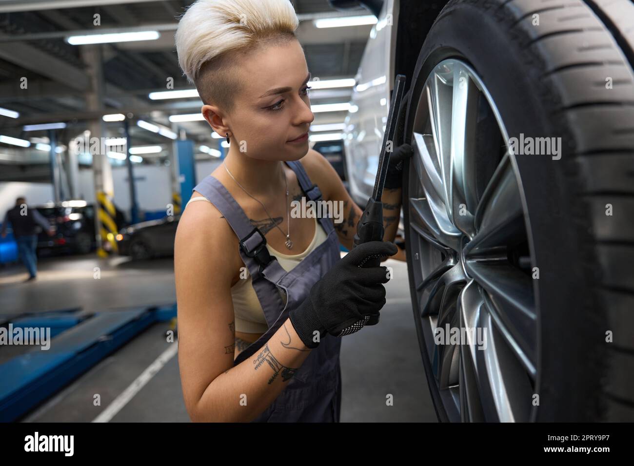 Woman car mechanic in work overalls checks a car wheel Stock Photo - Alamy