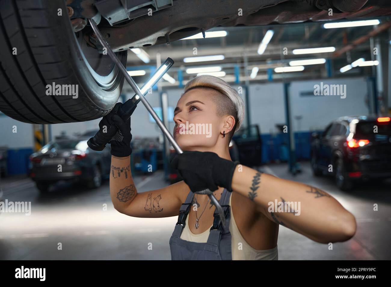 Car mechanic inspects the bottom of car raised on lift Stock Photo - Alamy