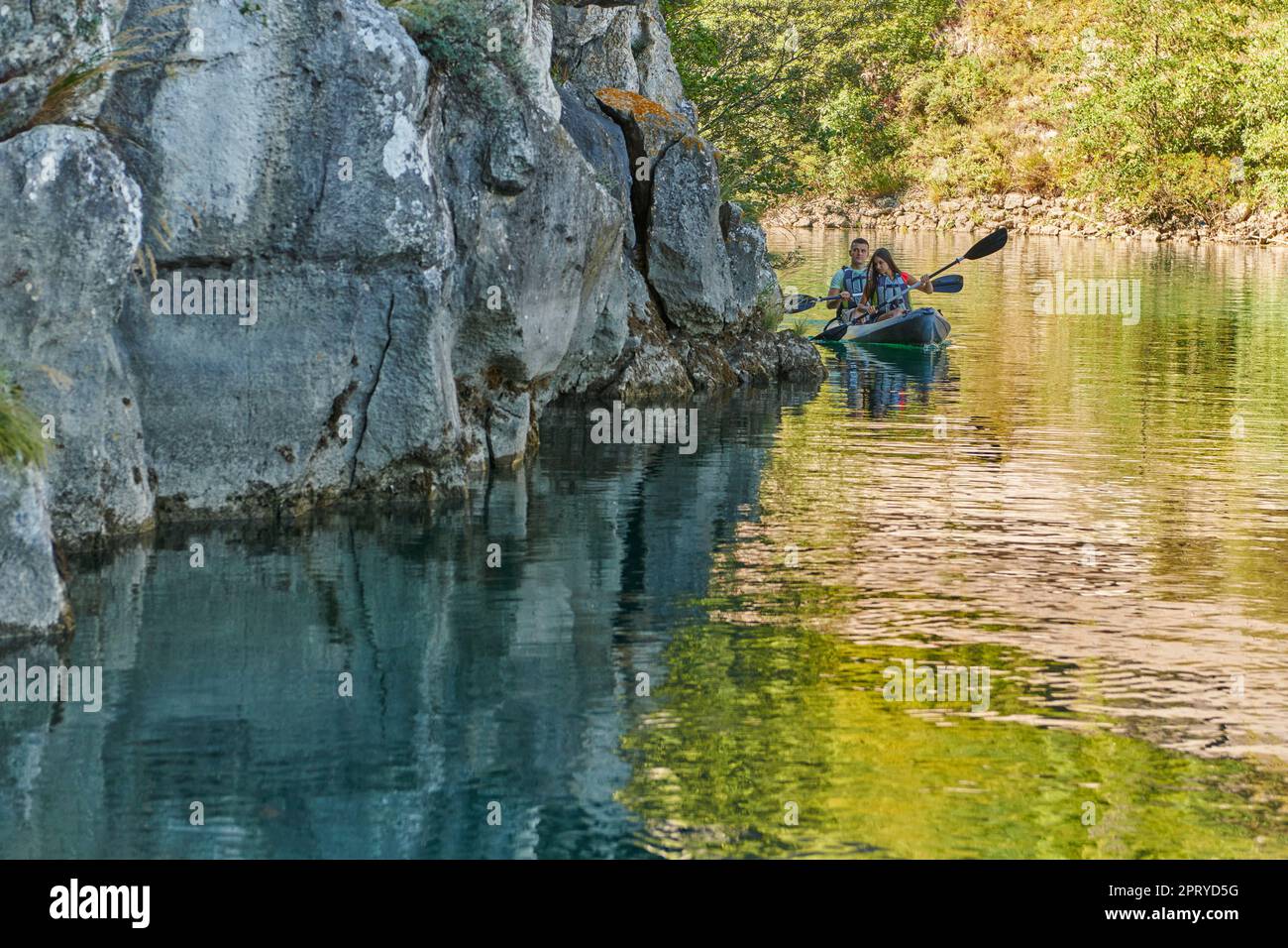 A young couple enjoying an idyllic kayak ride in the middle of a ...
