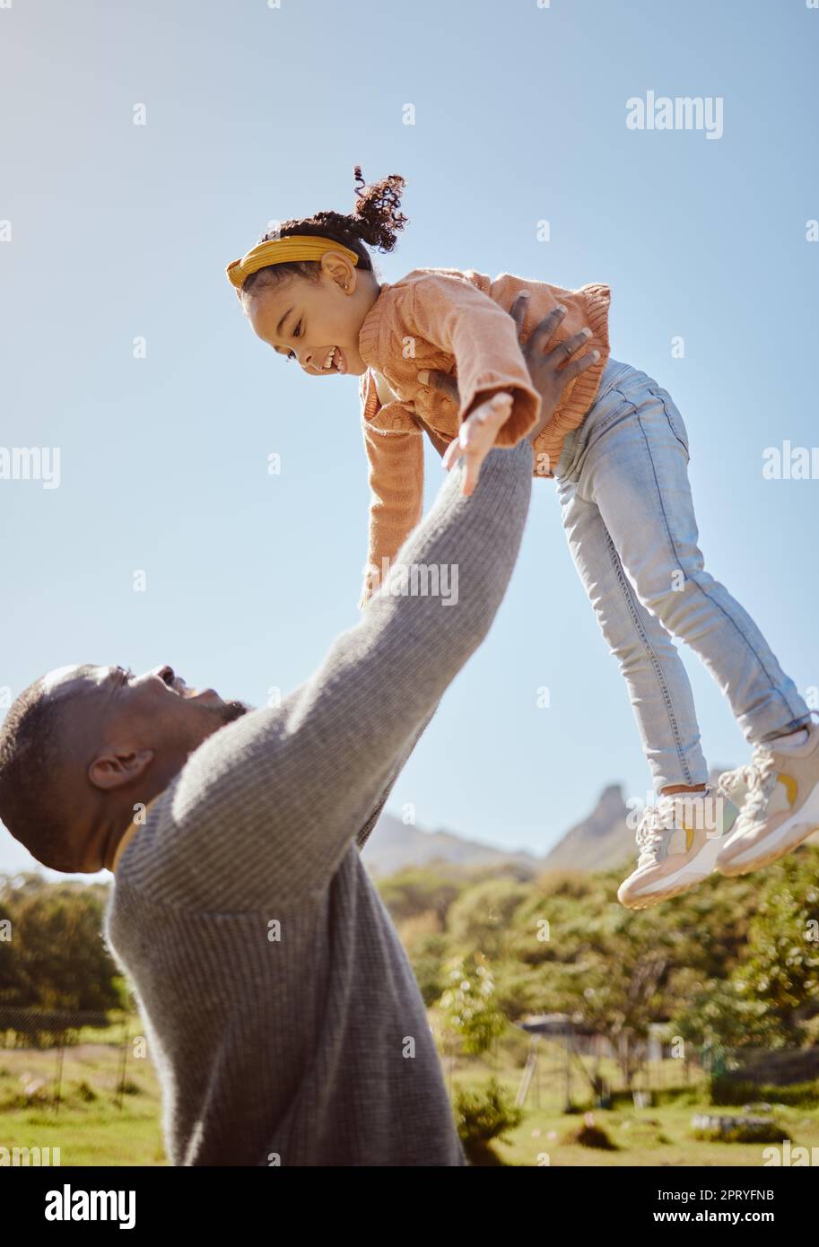 Father lifting kid in air at park, garden and nature outdoors for fun