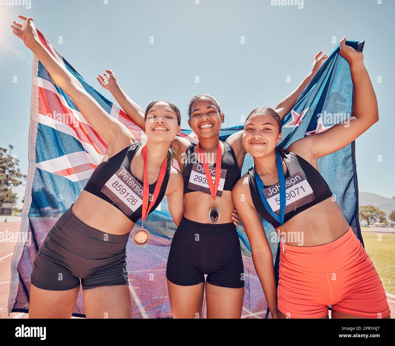 Winning, flag and athlete people or women team with medal for achievement, success and competition portrait on stadium. New Zealand sports champion or Stock Photo