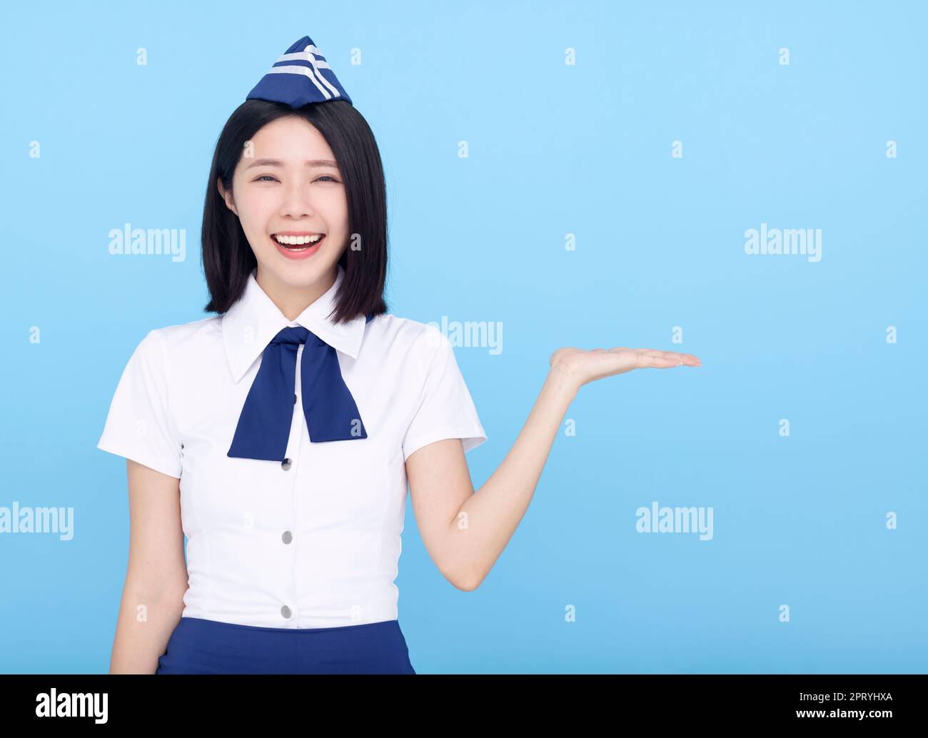 Happy Beautiful stewardess showing something on blue background Stock Photo