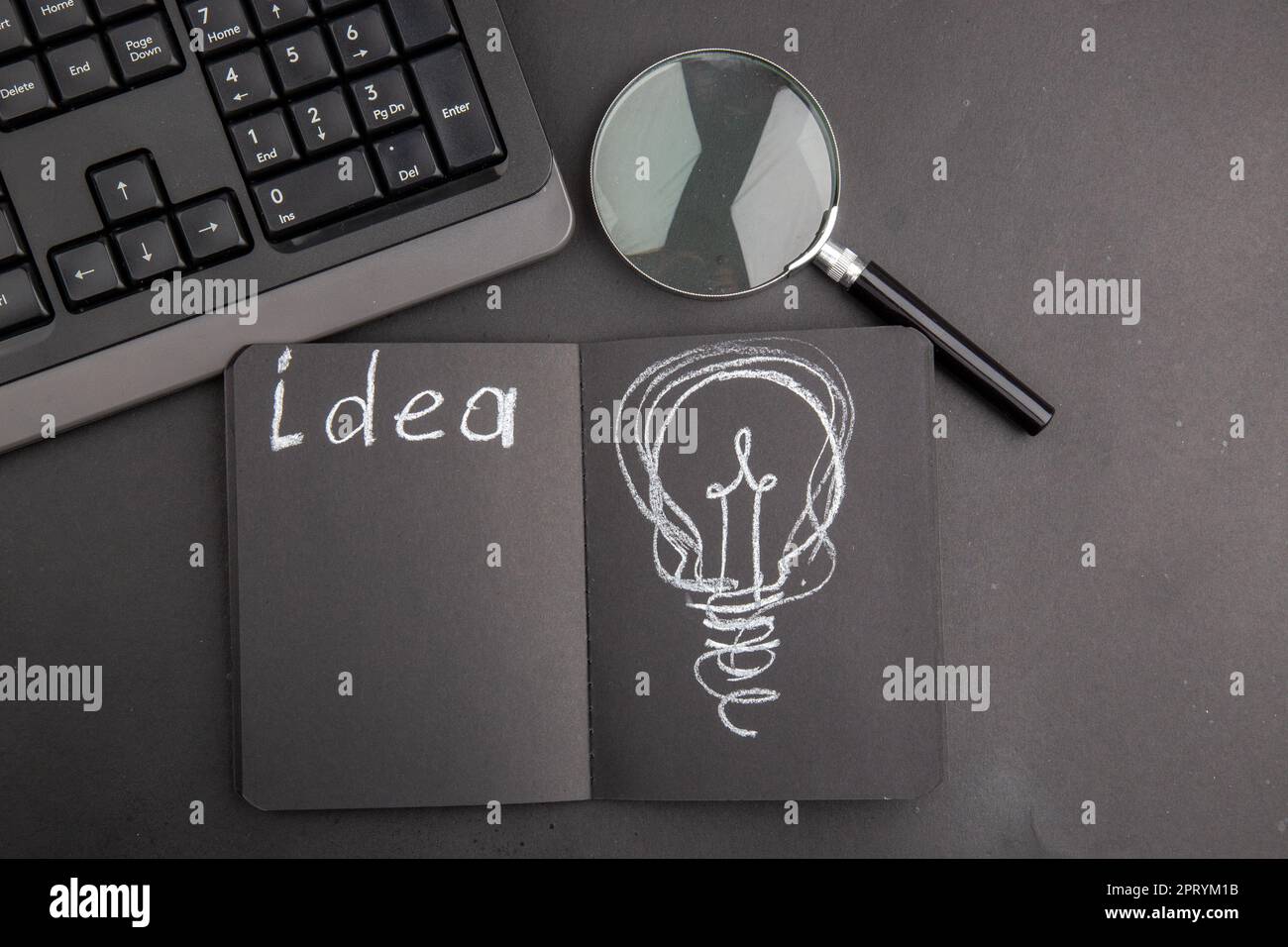 top view idea written on black notepad keyboard lupa on dark background Stock Photo