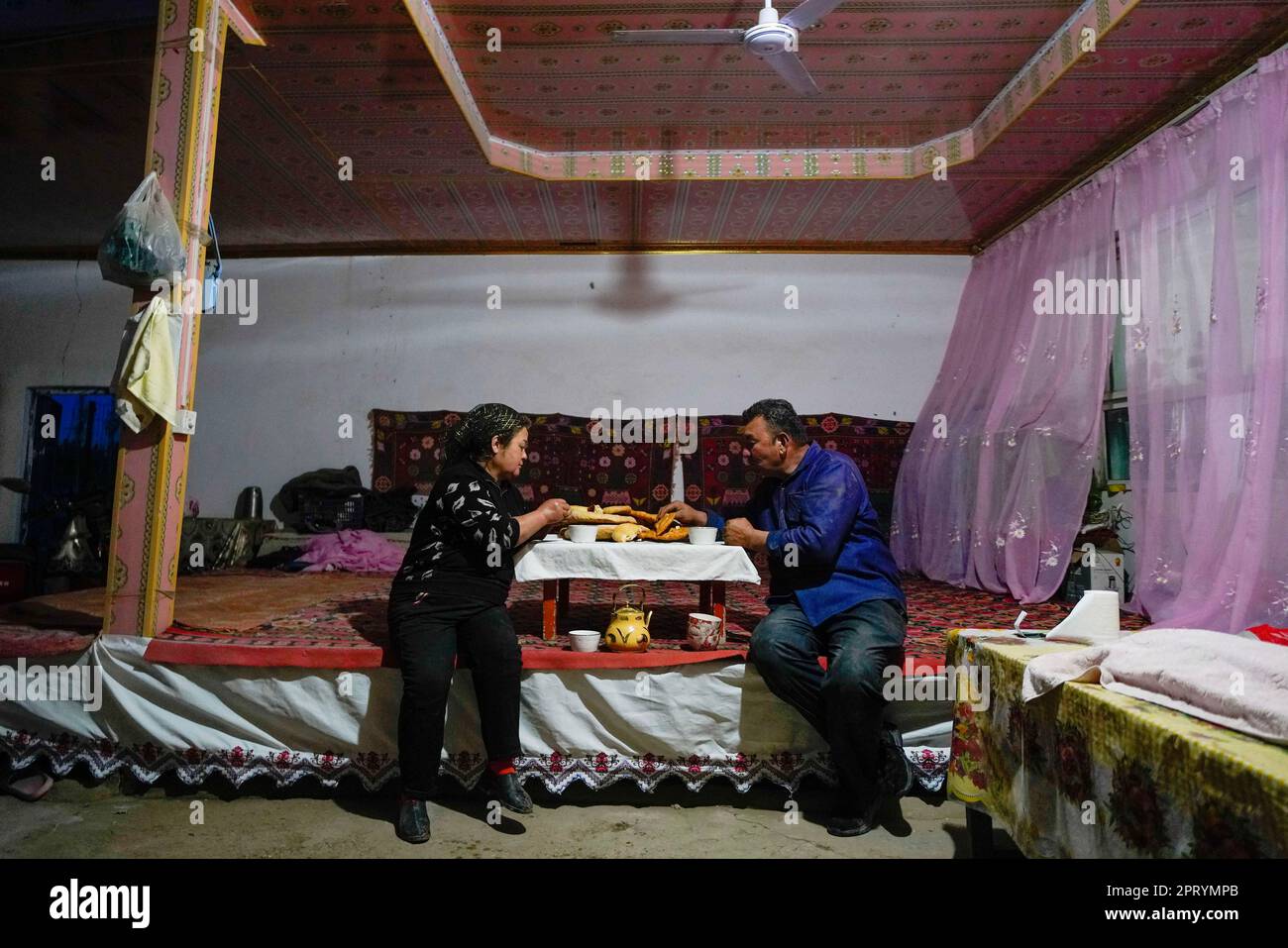 (230427) -- YULI, April 27, 2023 (Xinhua) -- Arkin Reyim has dinner with his wife in the Bax Mali Village of Yuli County, northwest China's Xinjiang Uygur Autonomous Region, April 21, 2023.  Arkin Reyim is a 51-year-old cotton farmer with more than 300 mu (20 hectares) of cotton fields in the Bax Mali Village of Yuli County in Xinjiang.     Arkin's courage and unique vision has prompted him to start growing cotton in 2004 when he got married with his wife Hasiyat Kasim. Since then, Arkin has devoted himself into the cultivation of cotton for over 10 years, thus making him an experienced cotton Stock Photo
