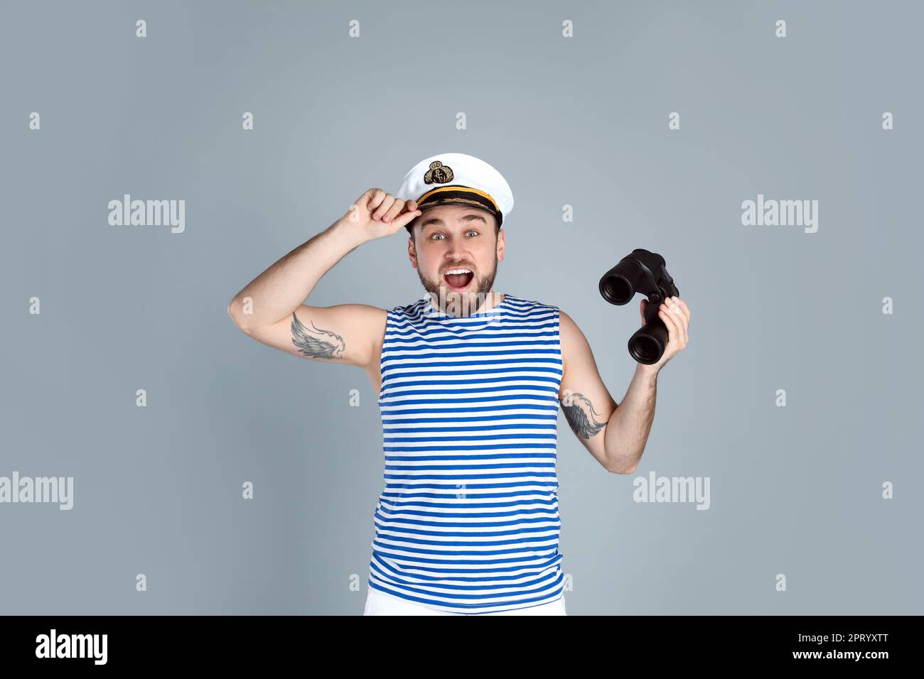 Emotional sailor with binoculars on light grey background Stock Photo