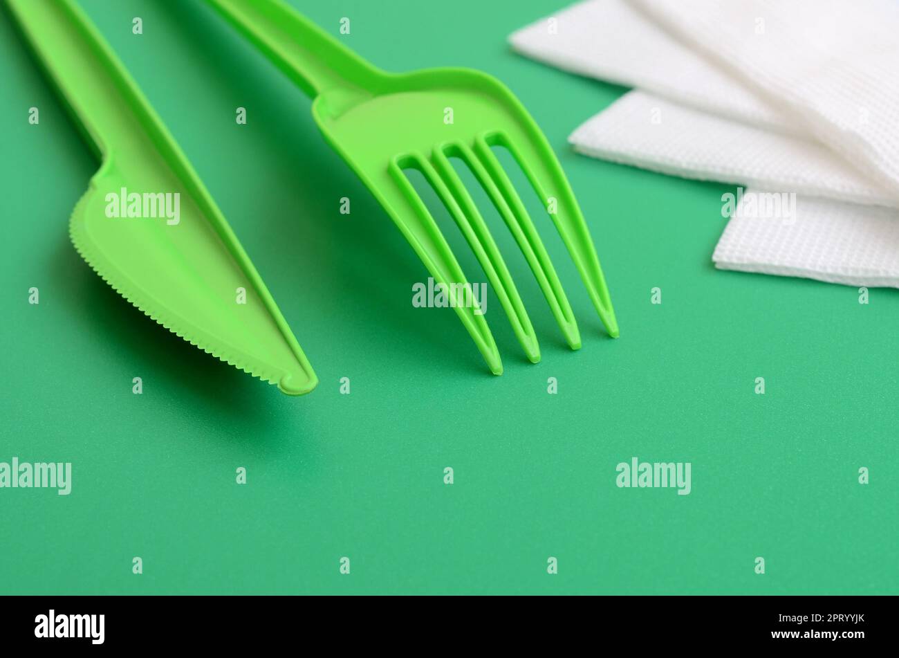 Disposable plastic cutlery green. Plastic fork and knife lie on a green