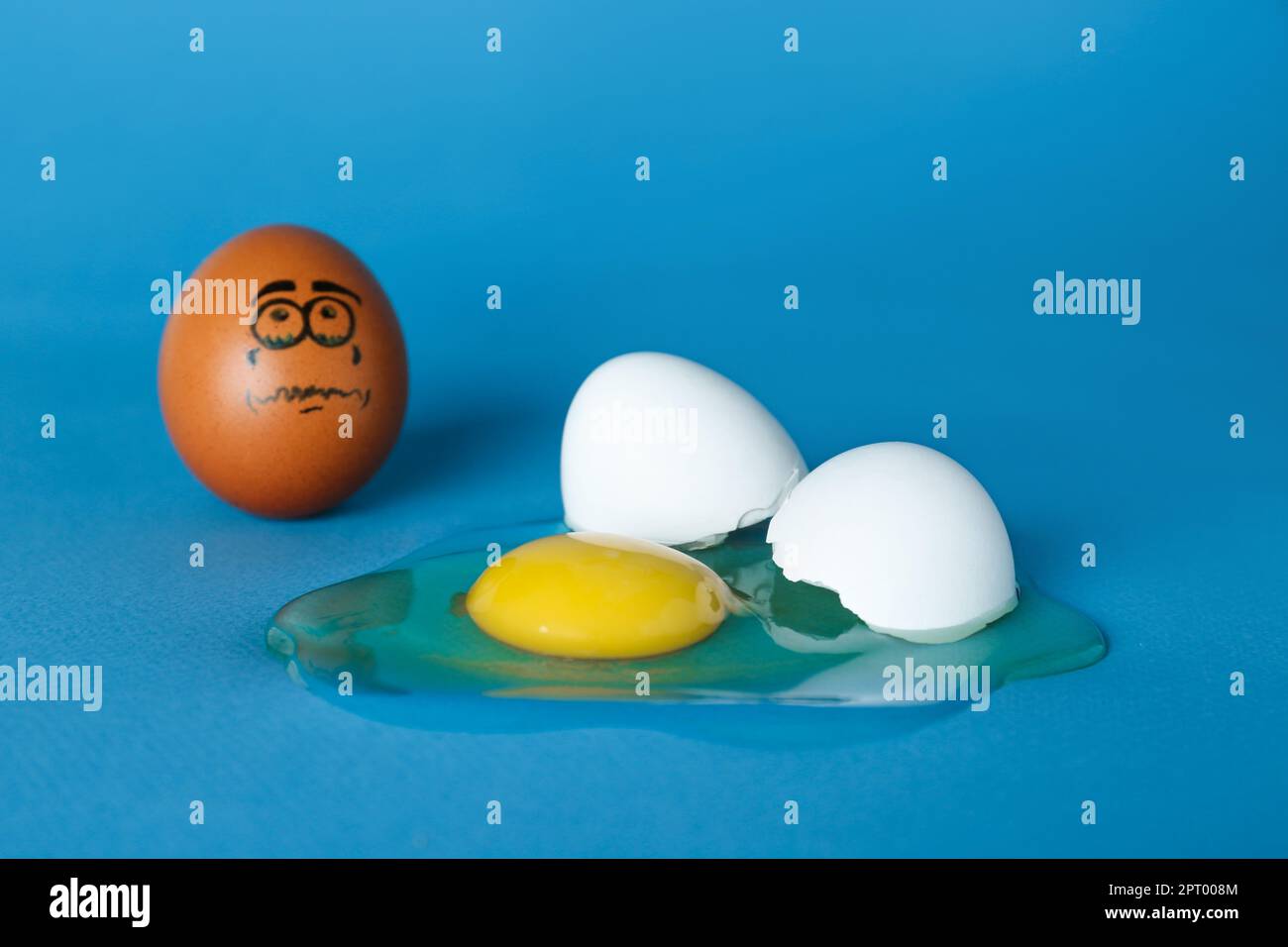 Whole egg with sad face and broken one on blue background Stock Photo