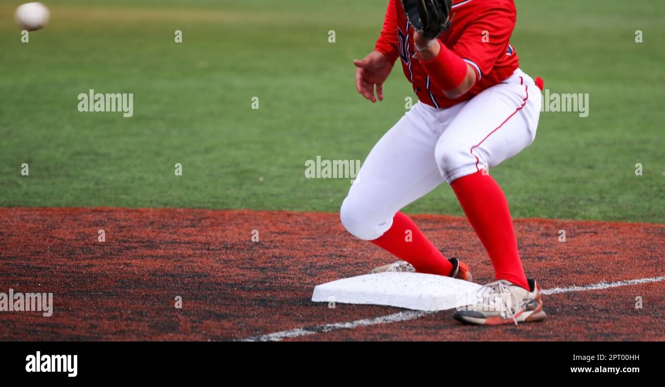 Ball thrown from the outfied to the third baseman to tag out the runner during a high school baseball game. Stock Photo