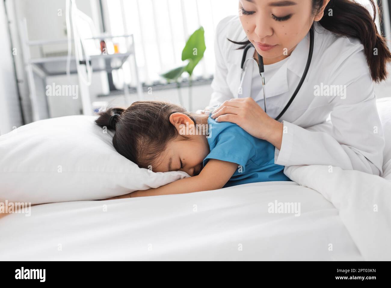 asian doctor calming depressed child obscuring face with pillow on ...
