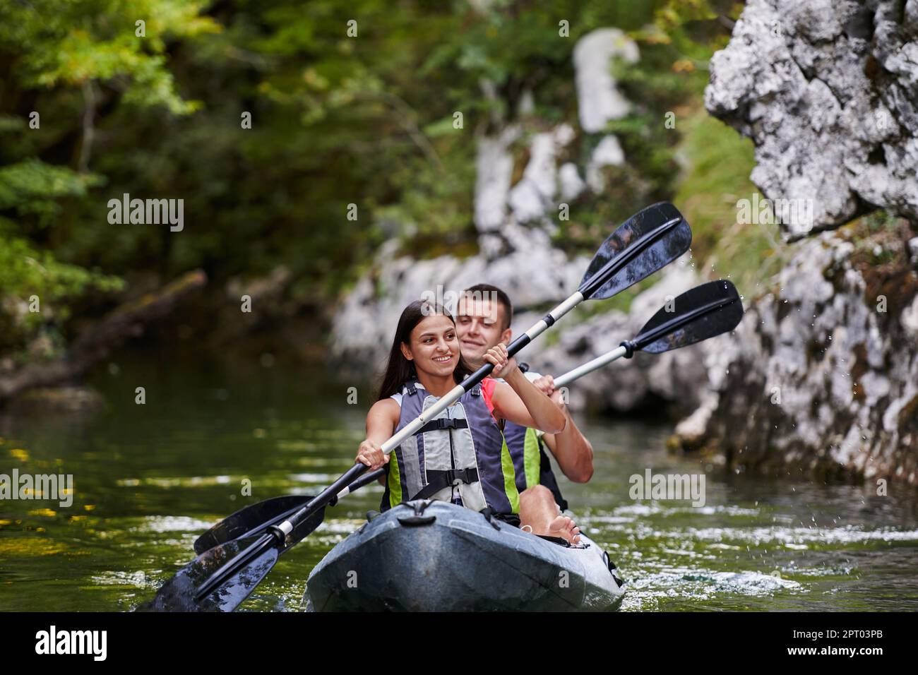 A young couple enjoying an idyllic kayak ride in the middle of a ...