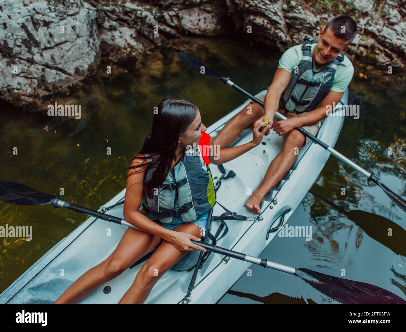 A young couple enjoying an idyllic kayak ride in the middle of a ...