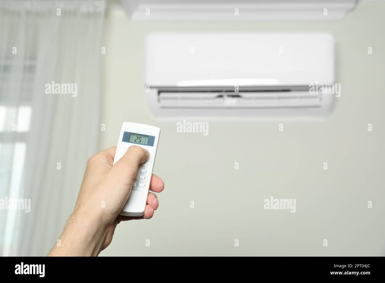 Man operating air conditioner with remote control indoors, closeup ...