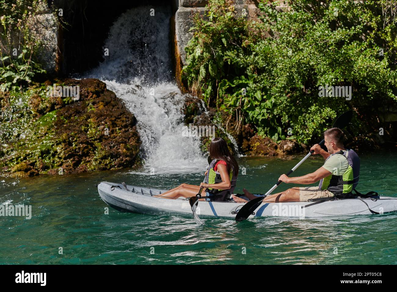 A young couple enjoying an idyllic kayak ride in the middle of a ...