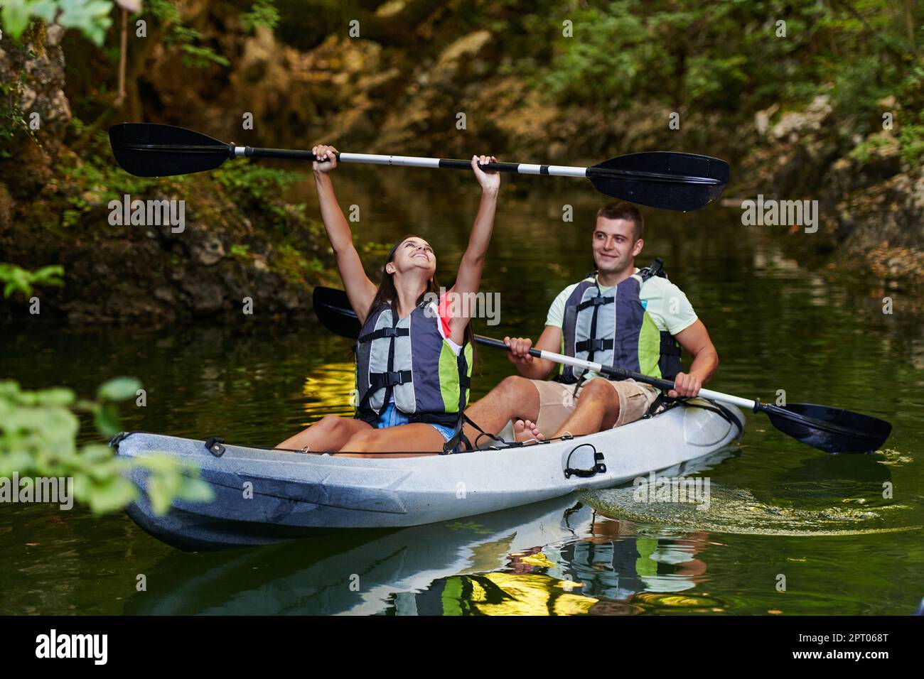 A young couple enjoying an idyllic kayak ride in the middle of a ...