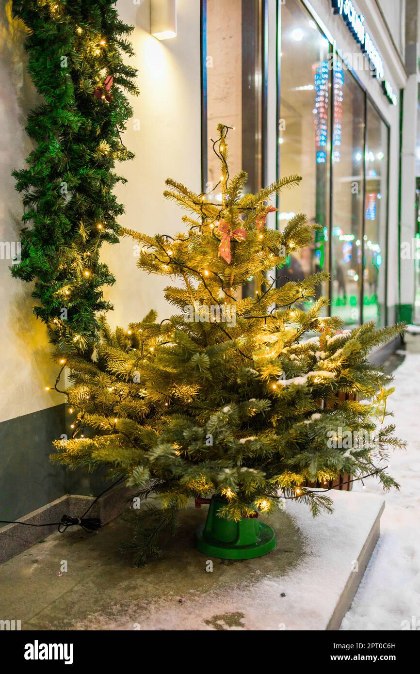 Christmas tree decorated with lights and New Year's garlands outside ...