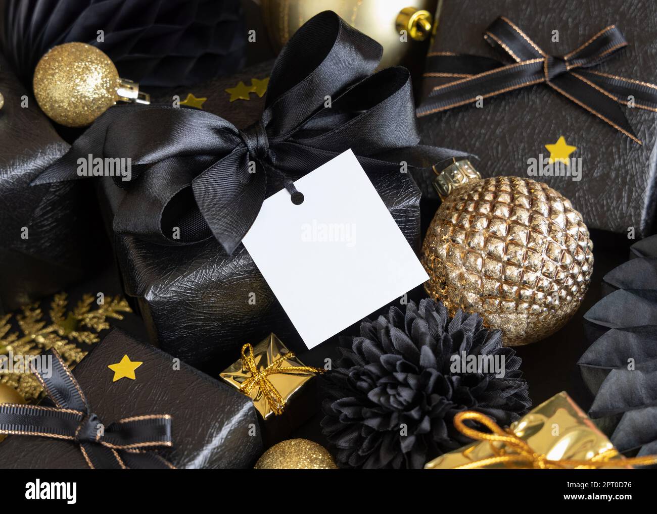 Black and golden Christmas Gift Boxes with a bow and ornaments close up,  square paper gift tag mockup, copy space. Dark winter composition with  blank Stock Photo - Alamy, image size:1300x1018