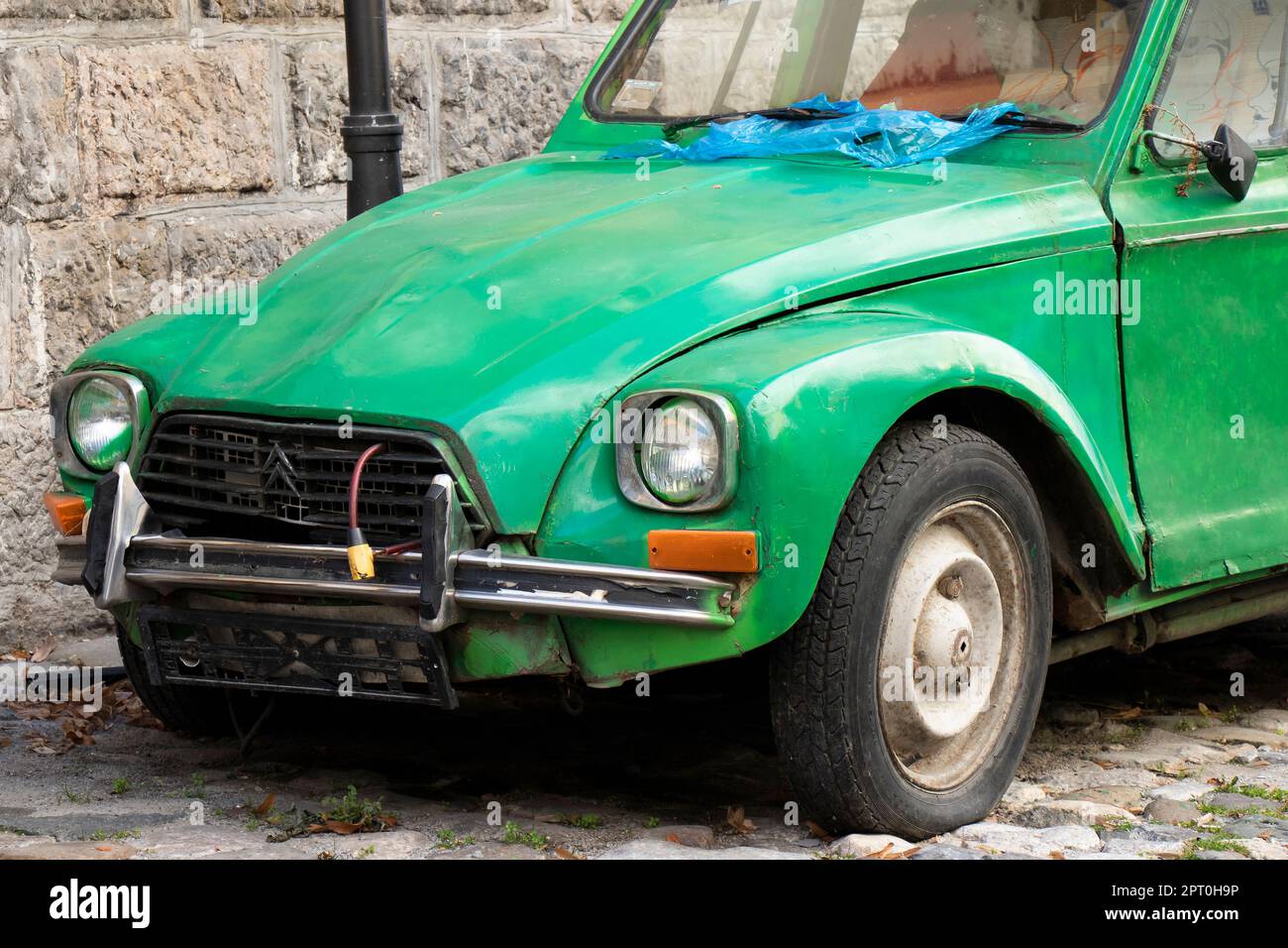 Belgrade, Serbia - February 23, 2023: Plate less weathered and damaged green old timer parked in the old cobble stone street. Stock Photo