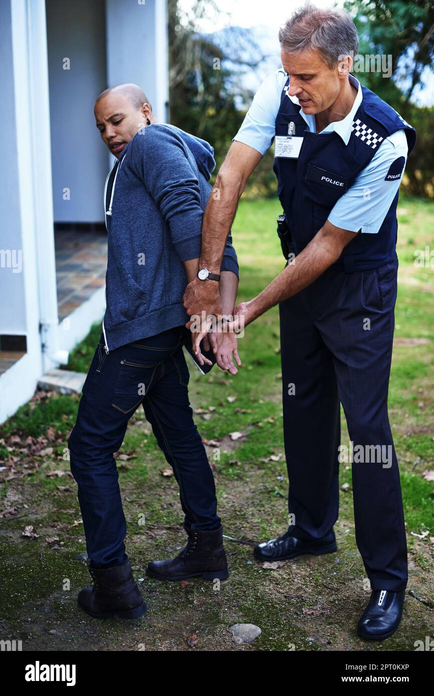 Gotcha. Full length shot of a man being handcuffed by a police officer Stock Photo