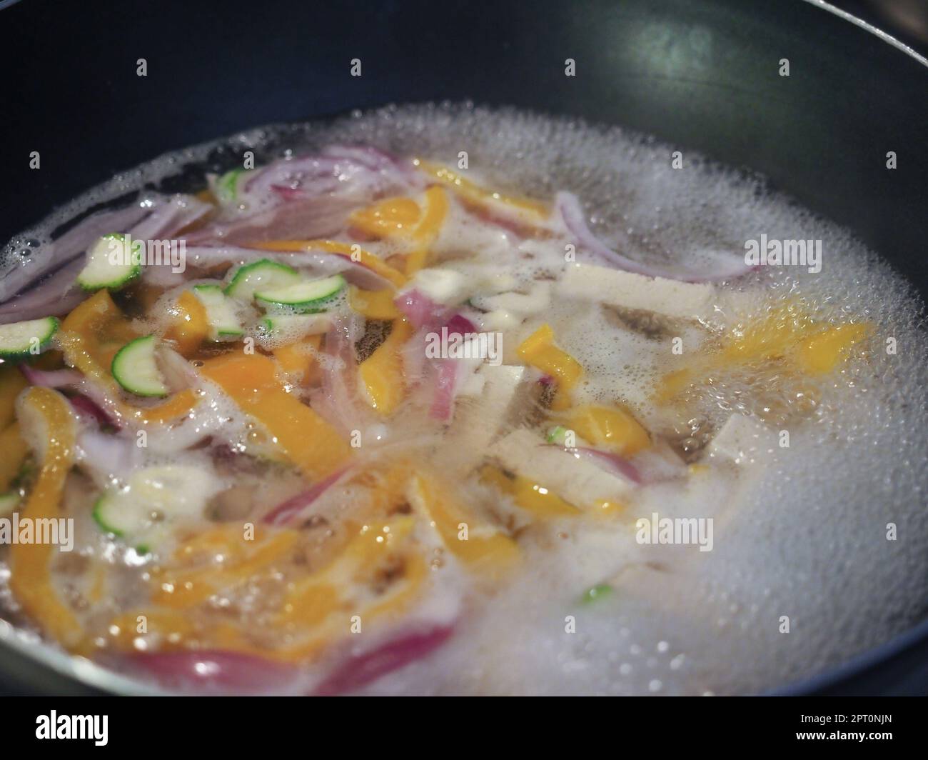 preparation of asian food with chopped vegetables and tofu frying in a ...