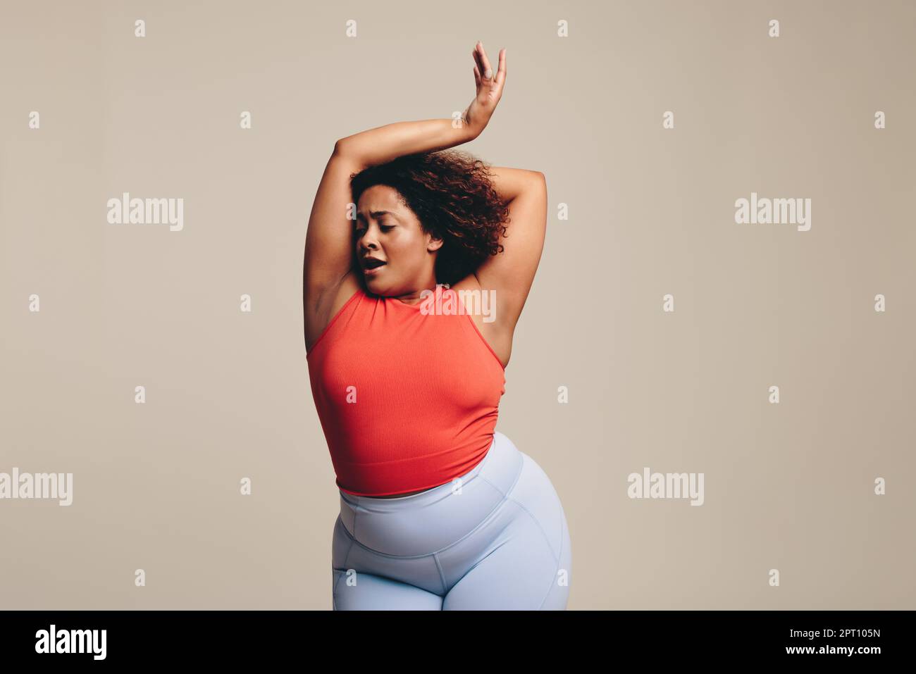 Fit woman with curves relishing in a dance workout, an expressive form of physical activity, in a studio setting. Woman celebrating her body, confiden Stock Photo