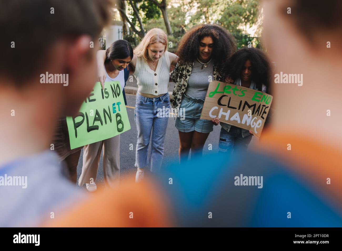 Group of multiethnic young people standing together in a circle at a climate change demonstration. Diverse youth activists joining the global climate Stock Photo