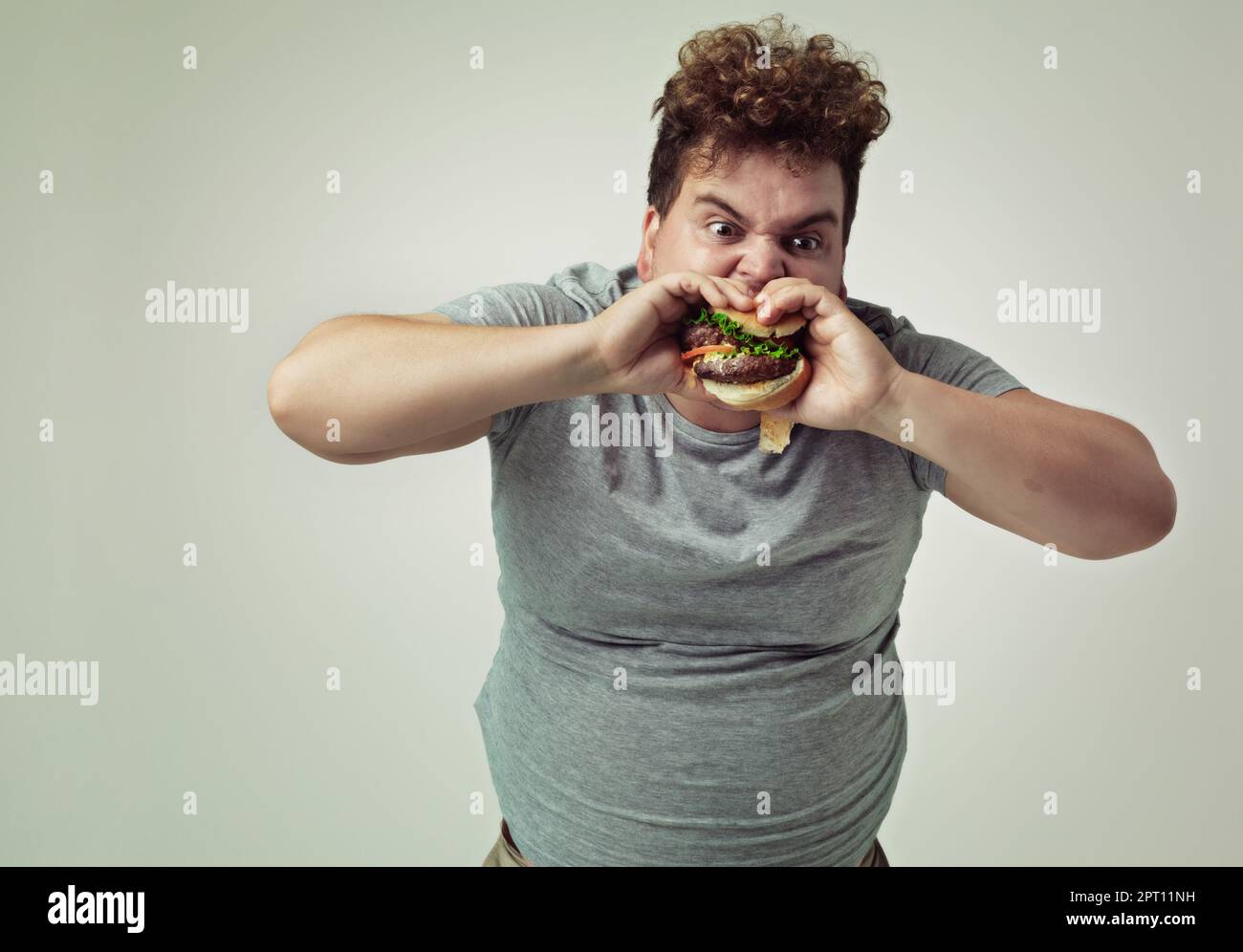 nothing-beats-a-good-burger-studio-shot-of-an-overweight-man-biting