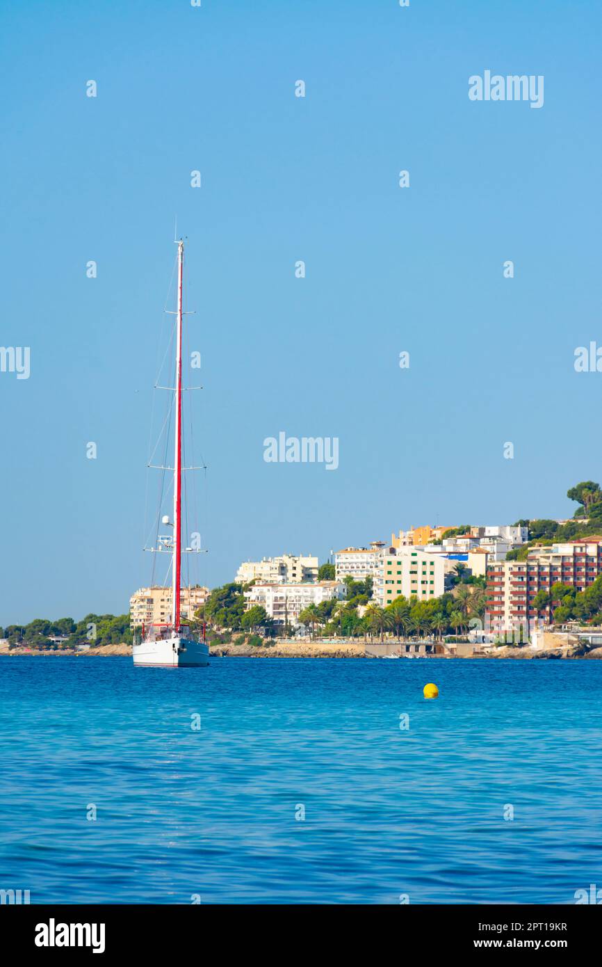 A yacht and a sailing boat moored in Cala Major cove. Ses Illetes at background, Majorca, Spain Stock Photo