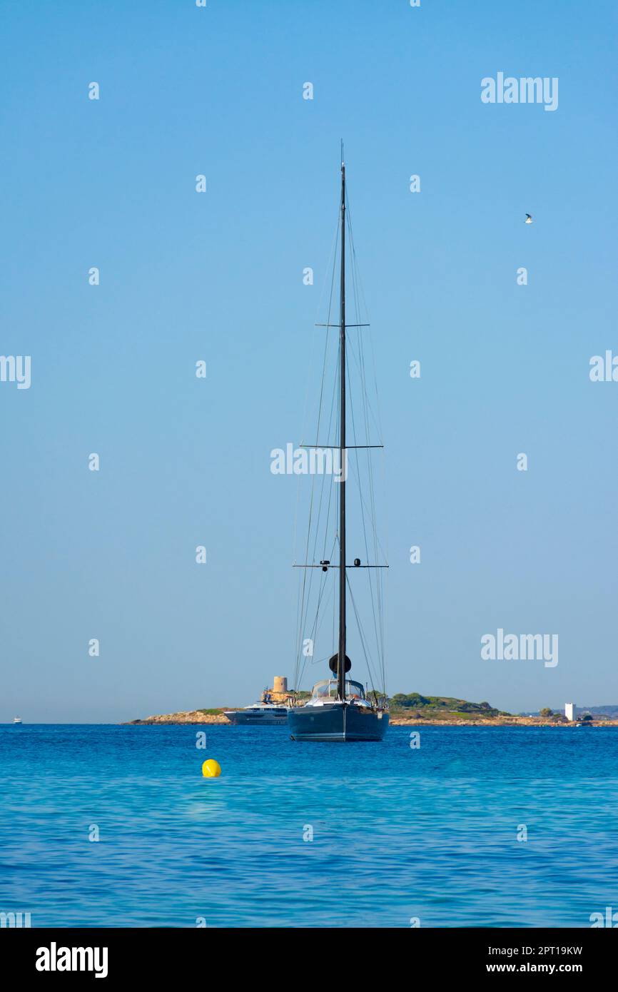 A sailing boat moored with the tower of Ses Illetes, Majorca, Spain Stock Photo