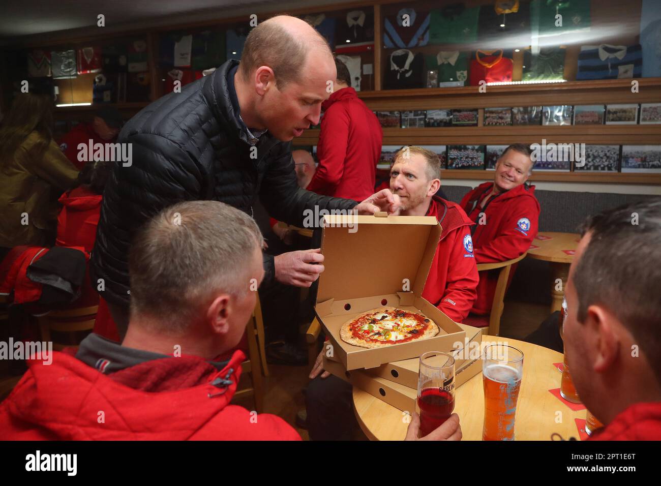 The Prince of Wales delivers take-away pizzas from a pizza van to rescue volunteers and supporters during a visit to Dowlais Rugby Club near Merthyr Tydfil in Wales. The volunteer-run organisation, which covers the central area of the Bannau Brycheiniog National Park including Pen y Fan, is celebrating its 60th birthday. Picture date: Thursday April 27, 2023. Stock Photo