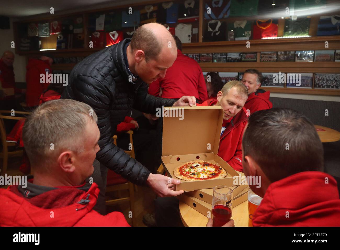 The Prince of Wales delivers take-away pizzas from a pizza van to rescue volunteers and supporters during a visit to Dowlais Rugby Club near Merthyr Tydfil in Wales. The volunteer-run organisation, which covers the central area of the Bannau Brycheiniog National Park including Pen y Fan, is celebrating its 60th birthday. Picture date: Thursday April 27, 2023. Stock Photo