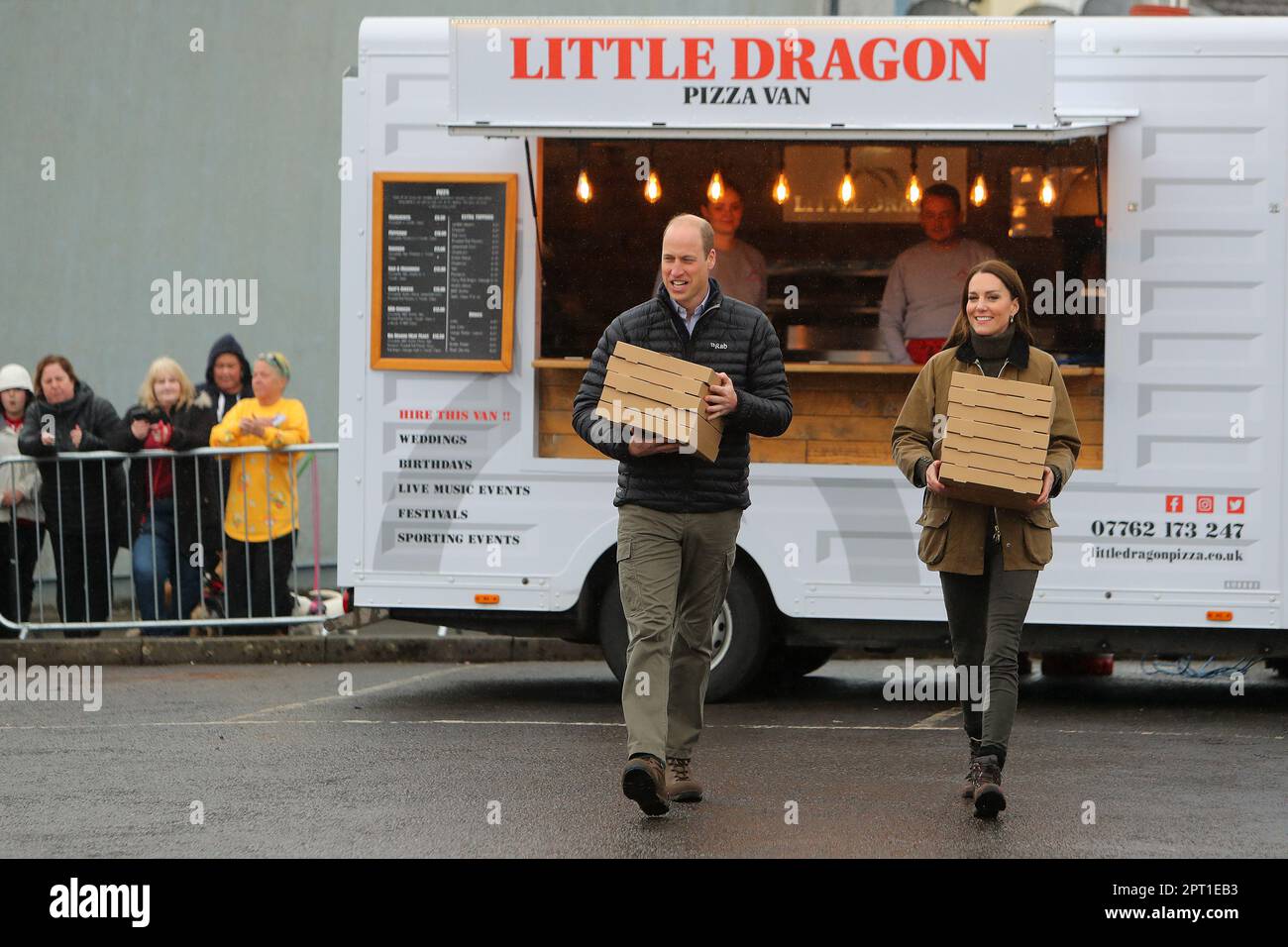 The Prince and Princess of Wales carry take-away pizzas from a pizza van as they meet mountain rescue volunteers and supporters during a visit to Dowlais Rugby Club near Merthyr Tydfil in Wales. The volunteer-run organisation, which covers the central area of the Bannau Brycheiniog National Park including Pen y Fan, is celebrating its 60th birthday. Picture date: Thursday April 27, 2023. Stock Photo