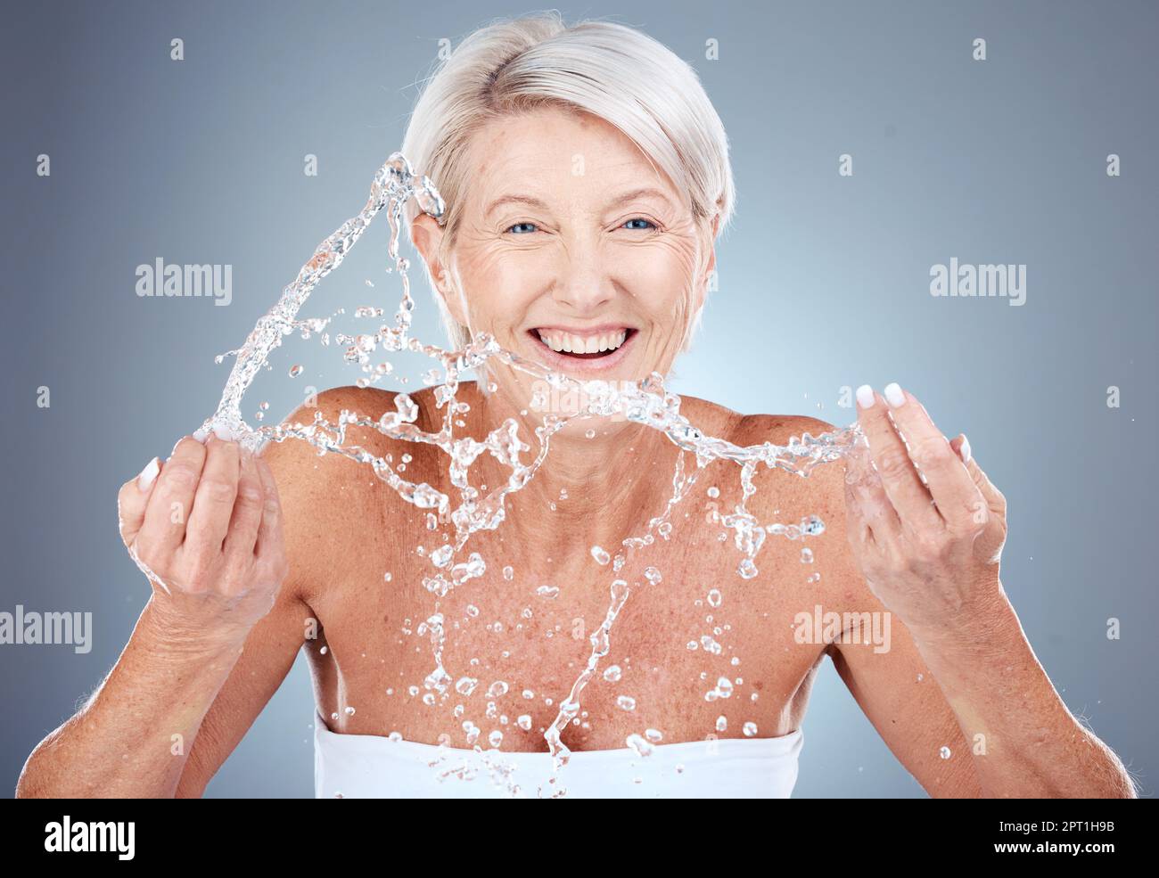 Water splash, mature woman cleaning face on gradient background for