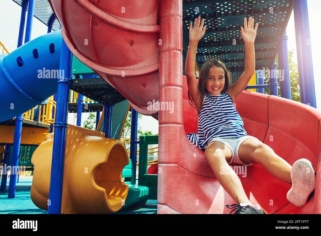 Sliding into the fun. a young girl sliding down the slide on a jungle gym  in the park Stock Photo - Alamy