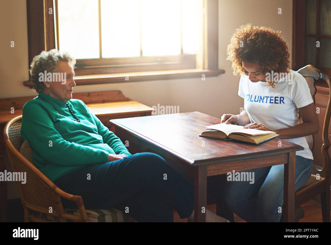 Sharing a love for reading. a volunteer reading to a senior woman at a