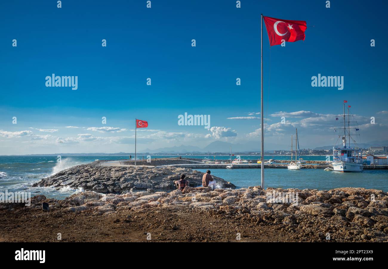 Turkish flags fly at the end of breakwaters marking the entrance to the habour at Side old town in Antalya Province, Turkey (Turkiye). Side is also th Stock Photo