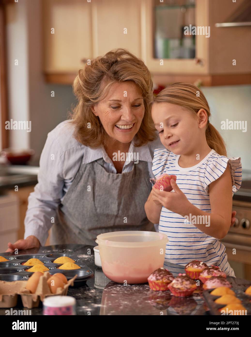 Youre doing a perfect job, my angel. a little girl decorating cupcakes with the help of her