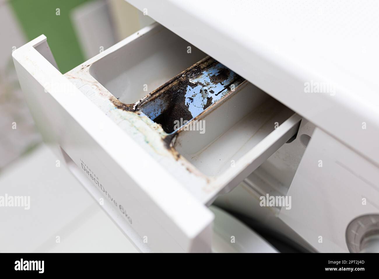 Close up dirty, moldy, pitted washing machine detergent dispenser after