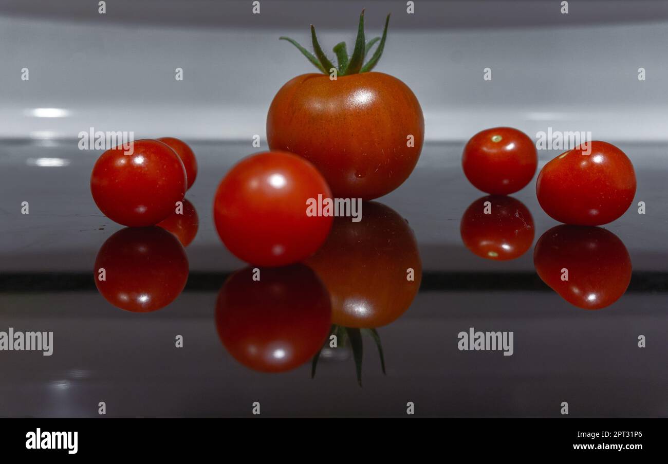 Red plumpy tomatoes with reflection from a dark reflective surface Stock Photo