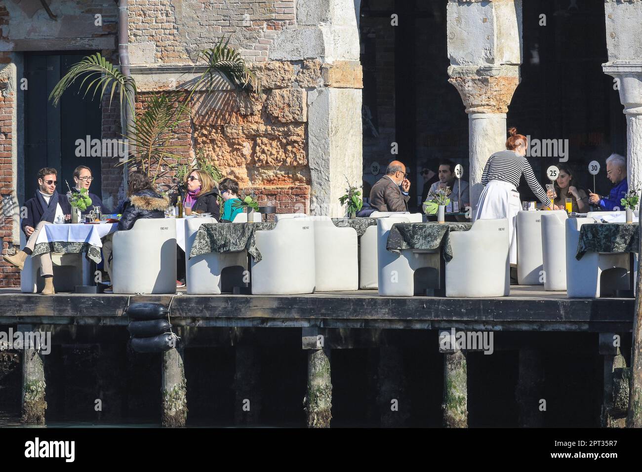 People dining outdoors in sunshine, balcony of a restaurant on the Grand Canal, Venice, Italy Credit: Imageplotter/Alamy Live News Stock Photo