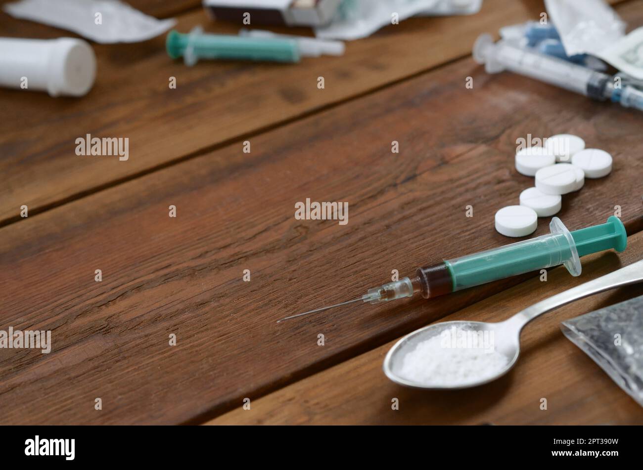 A lot of narcotic substances and devices for the preparation of drugs lie on an old wooden table. Drug dealer stuff. Heroin and methamphetamine in raw Stock Photo