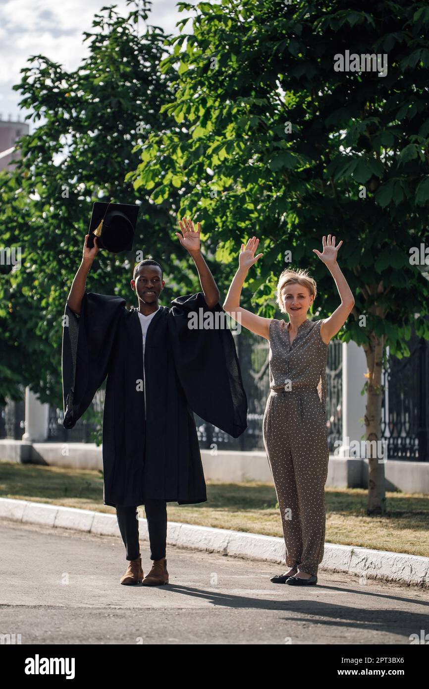 Afro american graduate from university in black mantle and hat with ...