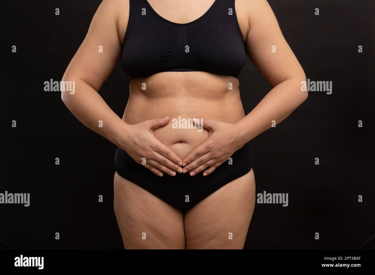 Fat woman in black underwear touch hanging belly. Flaunt figure