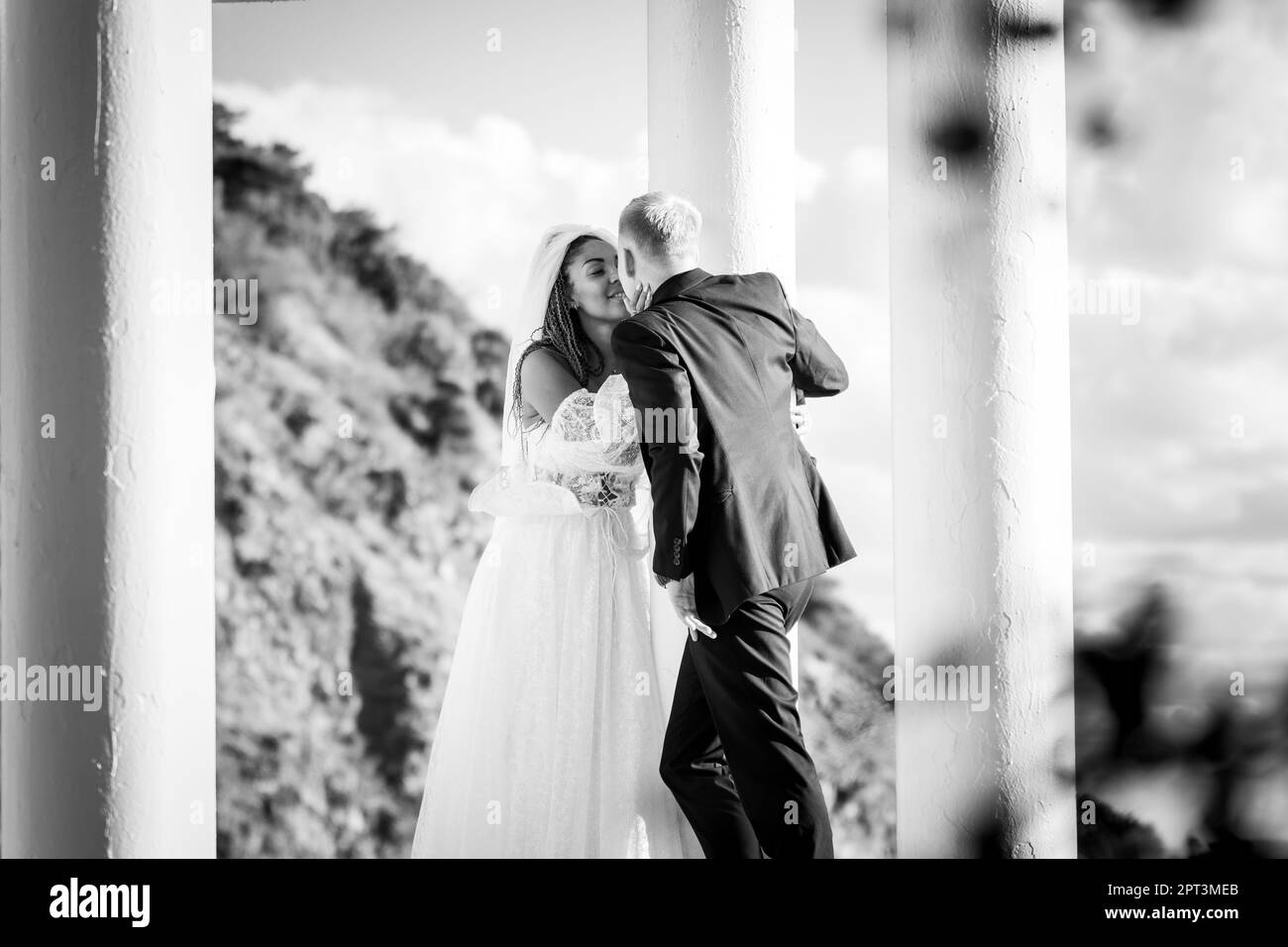 Happy newlyweds kiss in a beautiful gazebo with columns against the ...